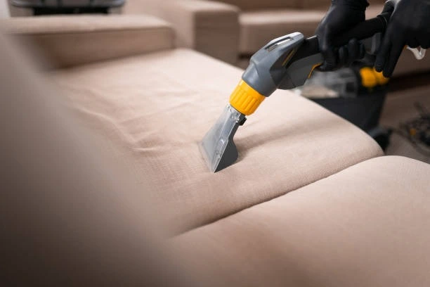Professional using an extraction machine on a beige sofa, demonstrating effective upholstery cleaning hacks for deep stain removal and fabric care.