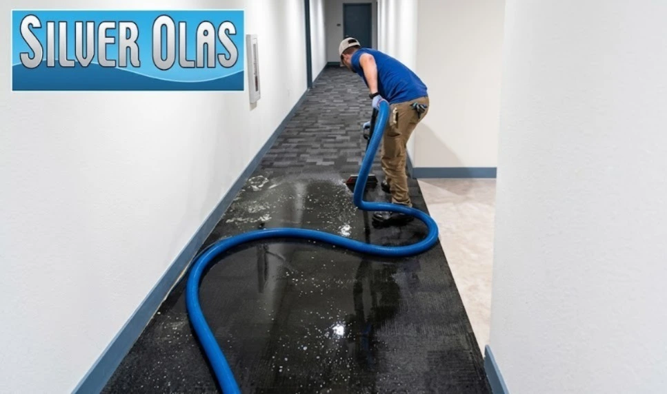 Professional technician from Silver Olas performing emergency flood water extraction on hallway carpet.