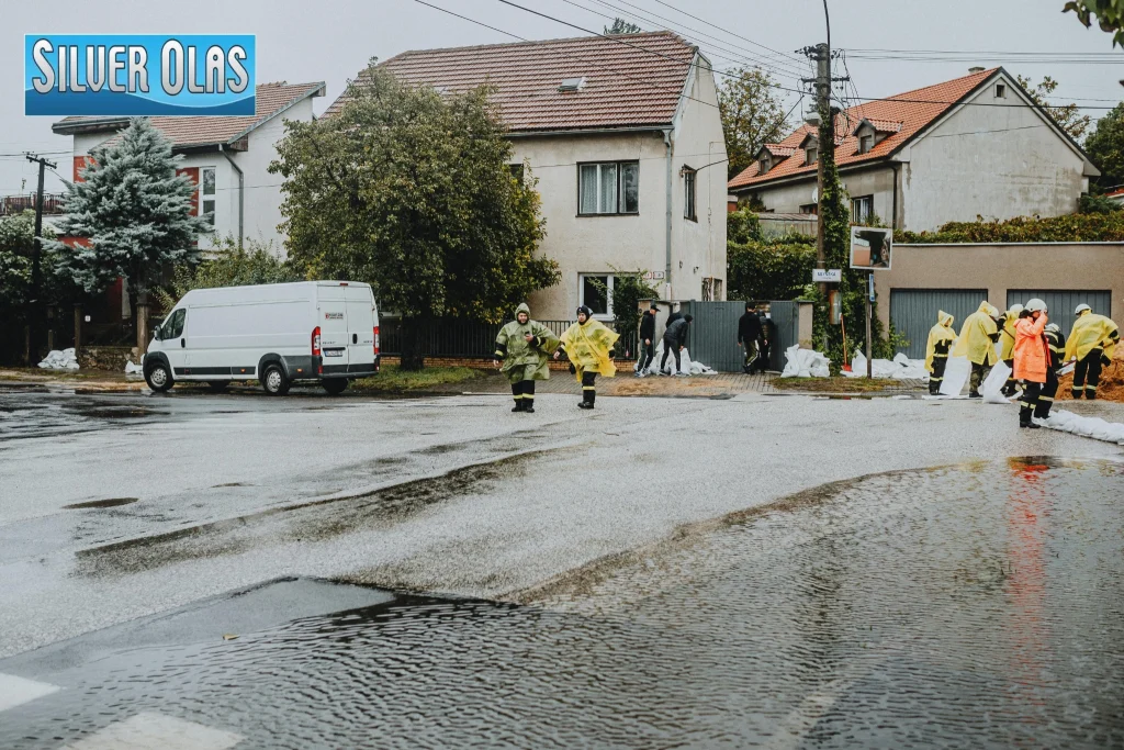 Emergency workers placing sandbags on a flooded neighborhood street.