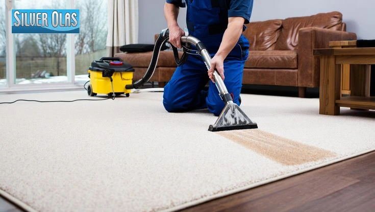 Professional cleaner using a steam machine to deep clean a white carpet.