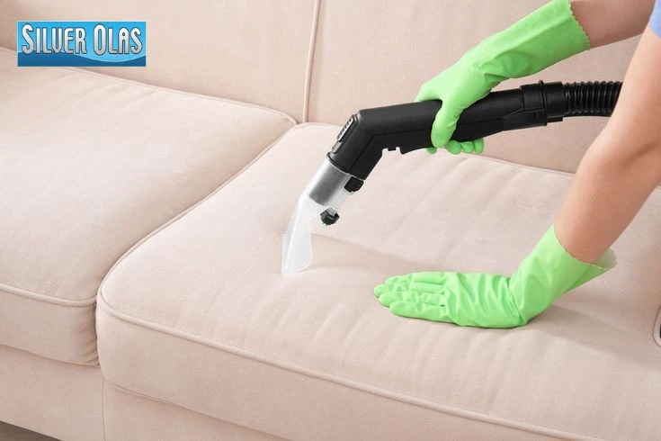 Professional upholstery cleaner near me in Carlsbad using a specialized steam extraction wand to deep clean a light-colored couch.