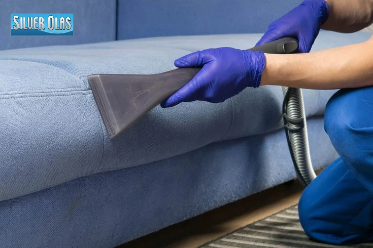 Professional carpet and upholstery cleaning services deep cleaning a blue fabric sofa.