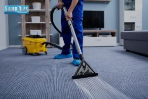 A professional carpet cleaning company technician vacuuming a blue ribbed carpet.