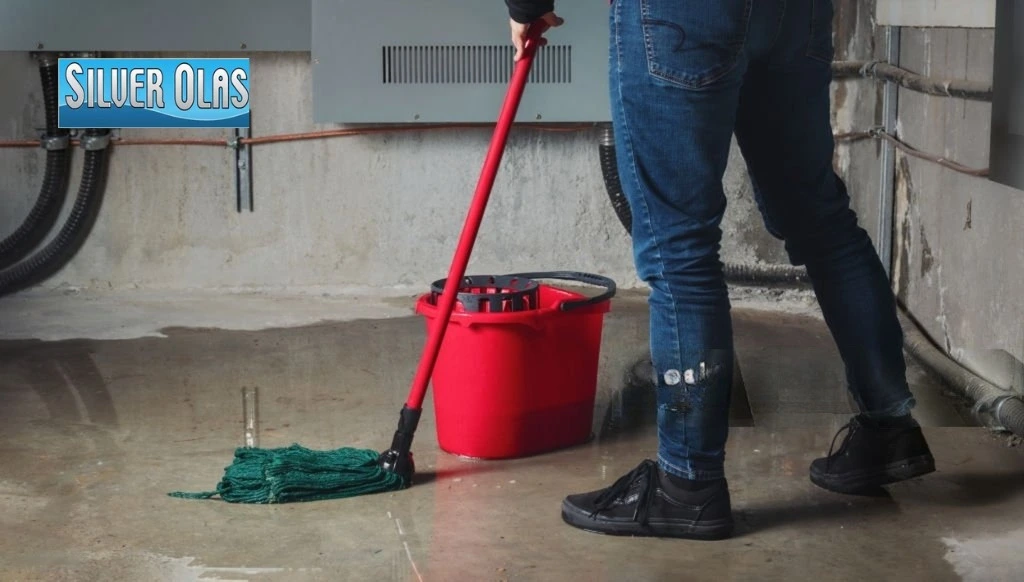 Professional basement flood cleanup services with a technician mopping a wet floor.