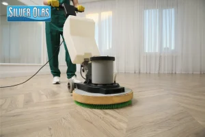 Professional cleaner operating floor buffer machine for wood floor cleaning services.
