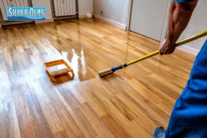 Professional applying protective finish to hardwood surface for wood floor maintenance tips.